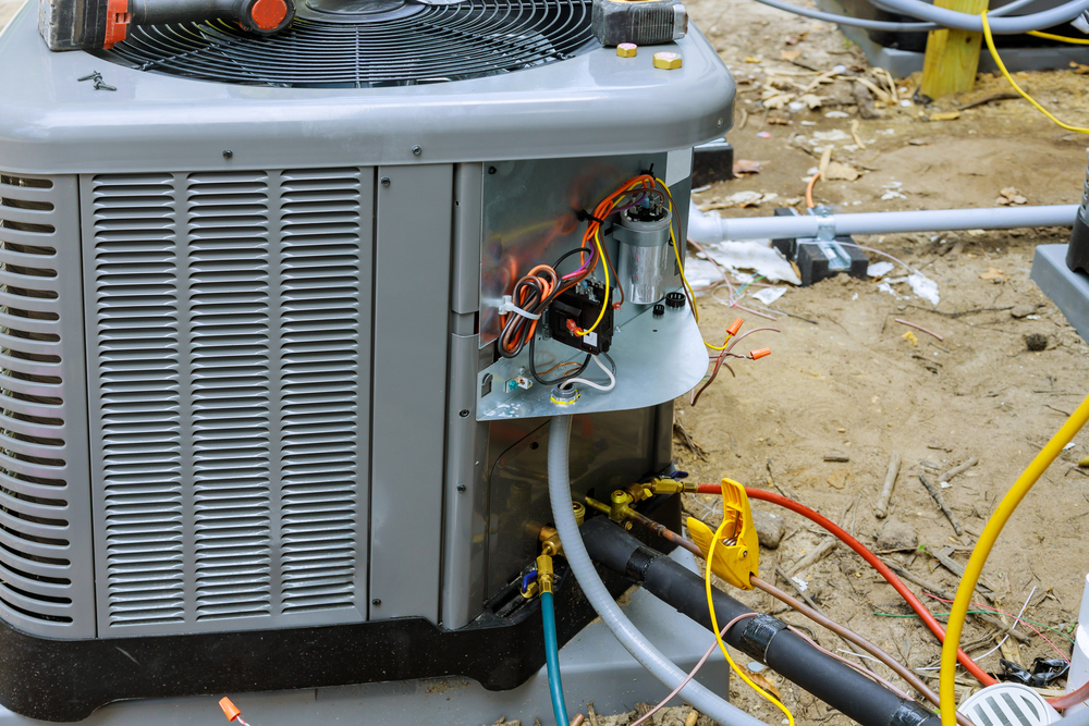 Technician inspecting air conditioner unit running but not cooling properly in a residential home