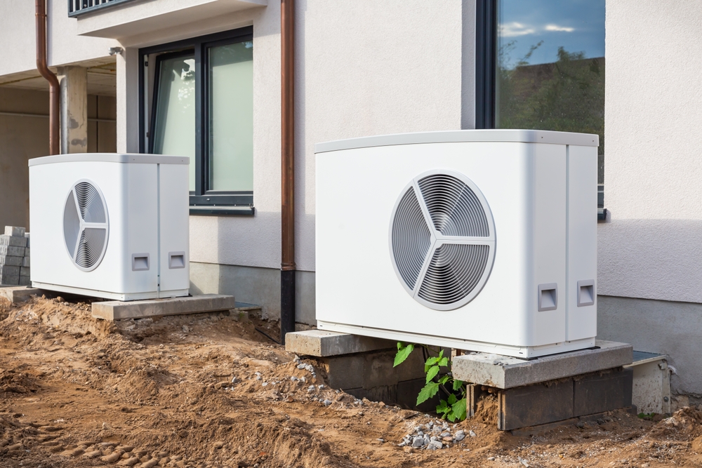 HVAC technician comparing a central AC unit and a heat pump during a residential system consultation